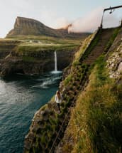 A girl climbs the ladder to get a better view of Mulafossur Waterfall in the Faroe Islands