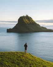 A man stands on the coast of the Faroe Islands, looking out at the ocean ahead of him