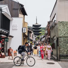 A busy street in Kyoto with a biker passing by taken by Erica Coble @filmandpixel