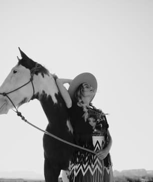 Black and white portrait of a woman and horse looking off in opposite directions.