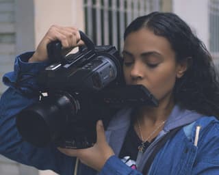 Kyndra Kennedy holding a camera on her shoulder and looking at the screen