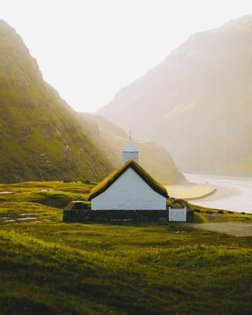 A small white church glows in the sunlight in one of the Faroe Island's many valleys