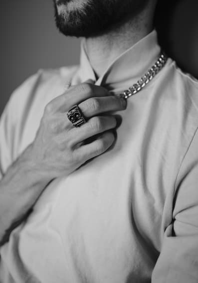 Black and white frame of a person touching their necklace.