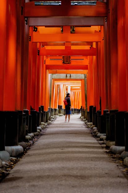 Woman standing in the Fushimi Inari Shrine in Kyoto taken by Michal Pechardo for a Moment photo trip to Japan with Neal Kumar