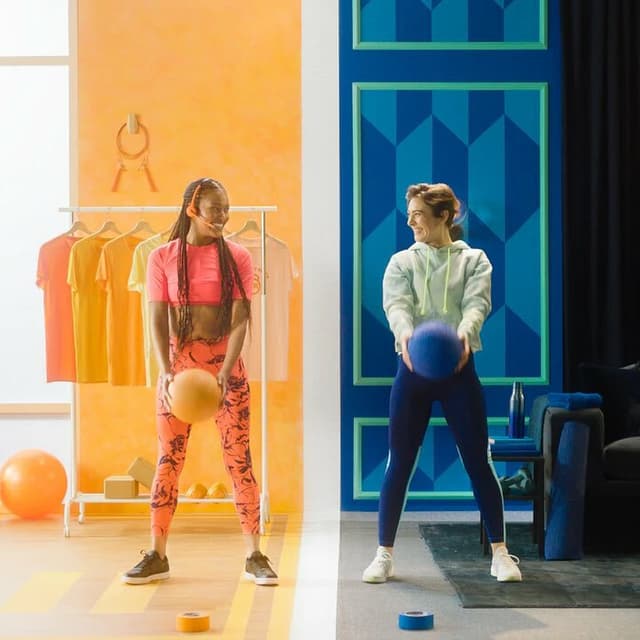 Two women holding exercise balls in a split toned orange and blue interior