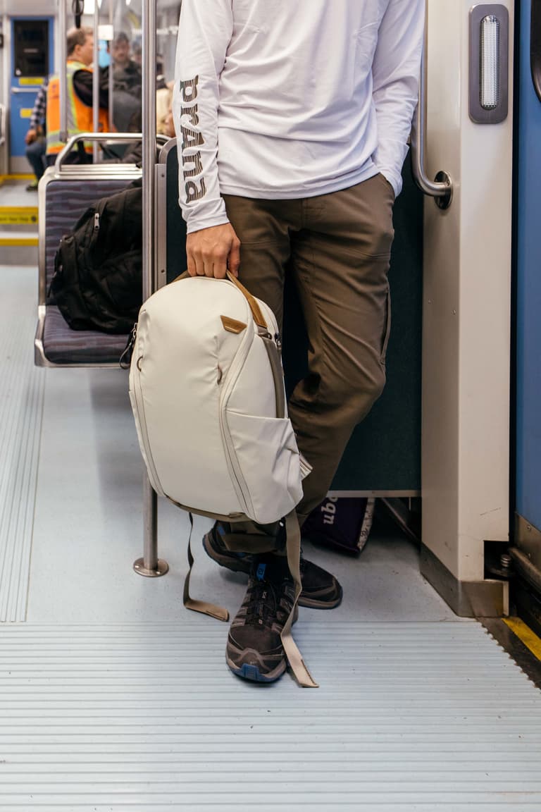 Peak Design Everyday Zip Backpack - Man wearing and adjusting Zip backpack on a Seattle train.