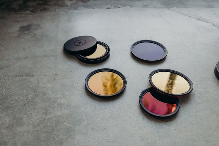 Five Moment Variable ND filters in different sizes and focal length ranges laying on a smooth cement surface