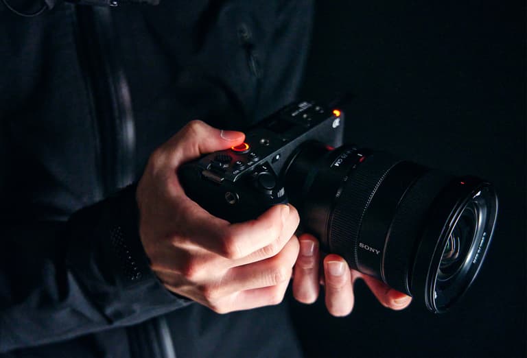 Moment Sony FX3 lifestyle hands holding camera dark