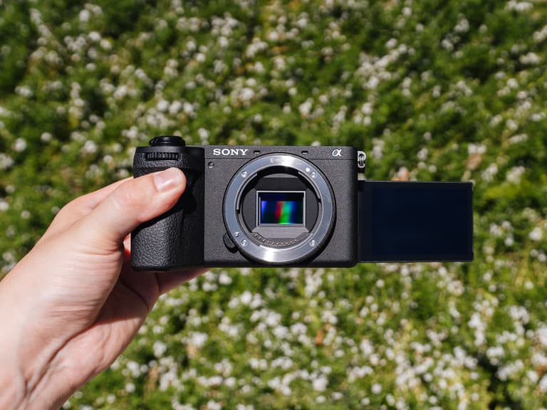 The Sony A6700 Review & Walkthrough — Image of a hand holding the camera up against a green outdoor background.