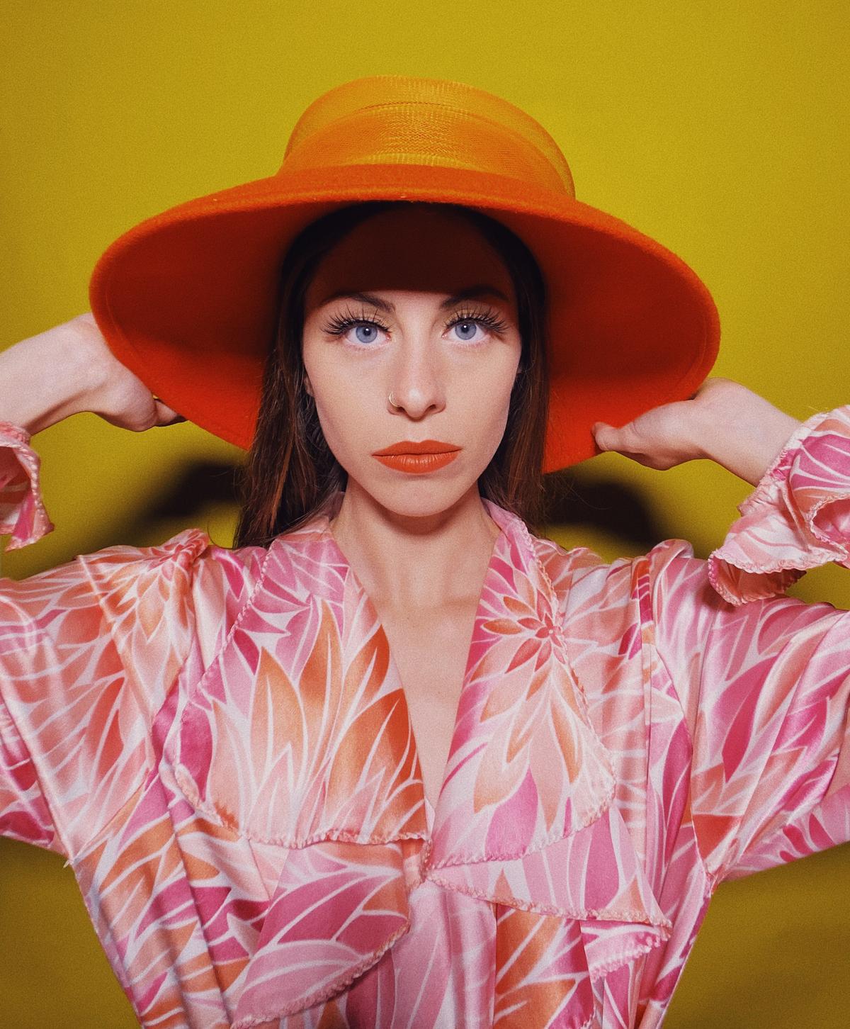 iPhone 11 - Portrait of young woman wearing pink robe and orange hat.