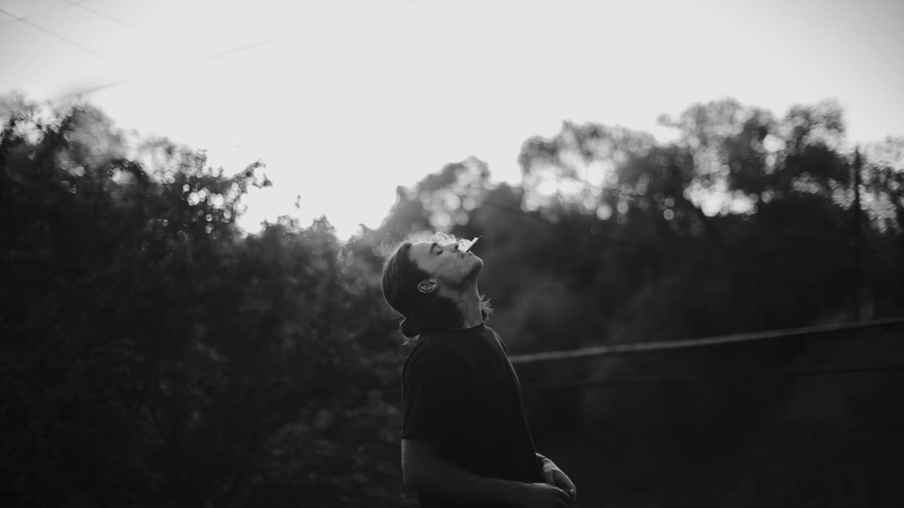 Black and white frame of a person exhaling smoke.