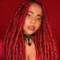 Sade Ndya headshot with long red hair on a red background