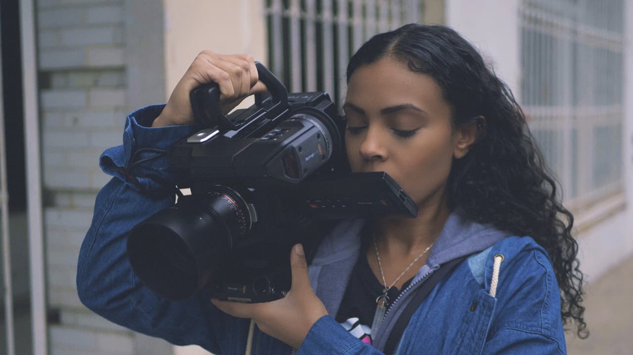 Kyndra Kennedy holding a camera on her shoulder and looking at the screen