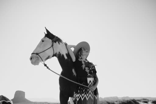 Black and white portrait of a woman and horse looking off in opposite directions.