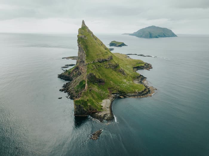 A small island in the Faroes juts out of the blue ocean