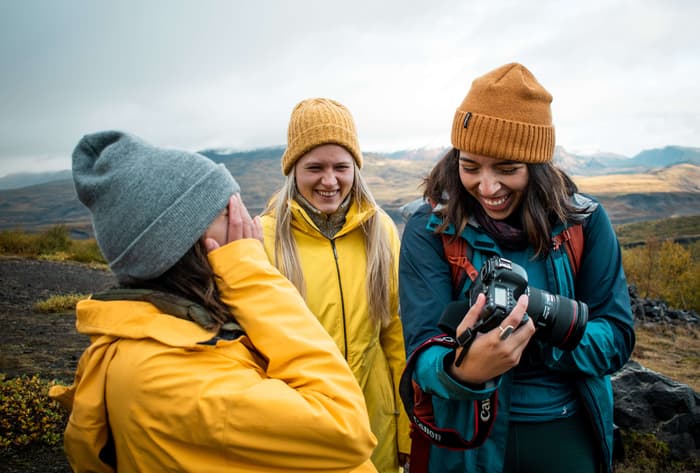 Three girls in bright jackets looking at a photo on a camera in Iceland